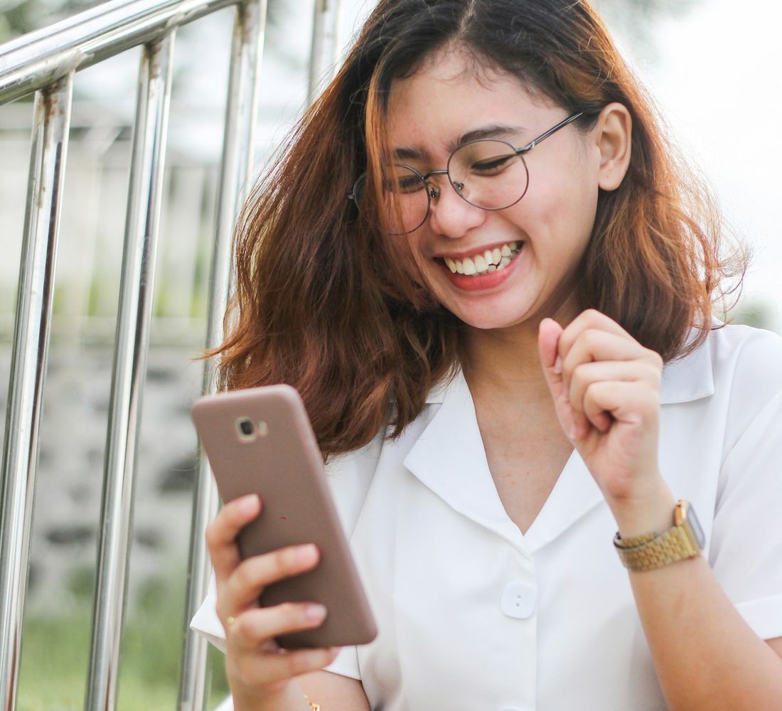 Cô gái trẻ cười khi xem video trên điện thoại