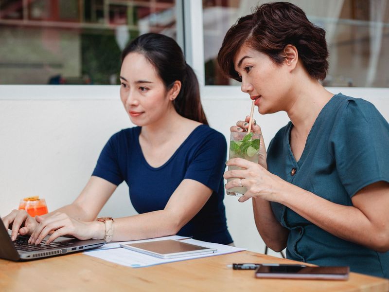 Hai người phụ nữ làm việc với máy tính xách tay tại quán cà phê