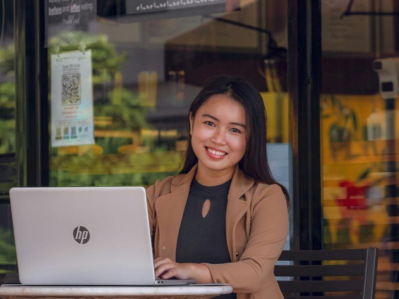 Chủ cơ sở kinh doanh nhỏ mỉm cười bên máy tính tại cửa hàng